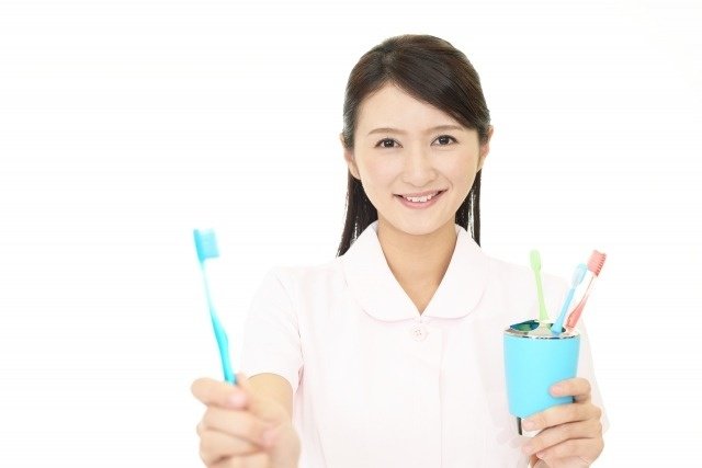 笑顔で歯ブラシを持つ歯科衛生士