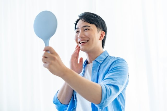 鏡を見て笑っている男性