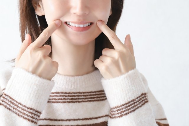 口角に指先を添えている女性の口元